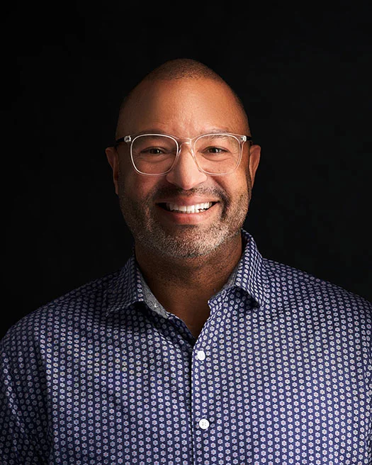 Marcos A., smiling in a patterned blue shirt